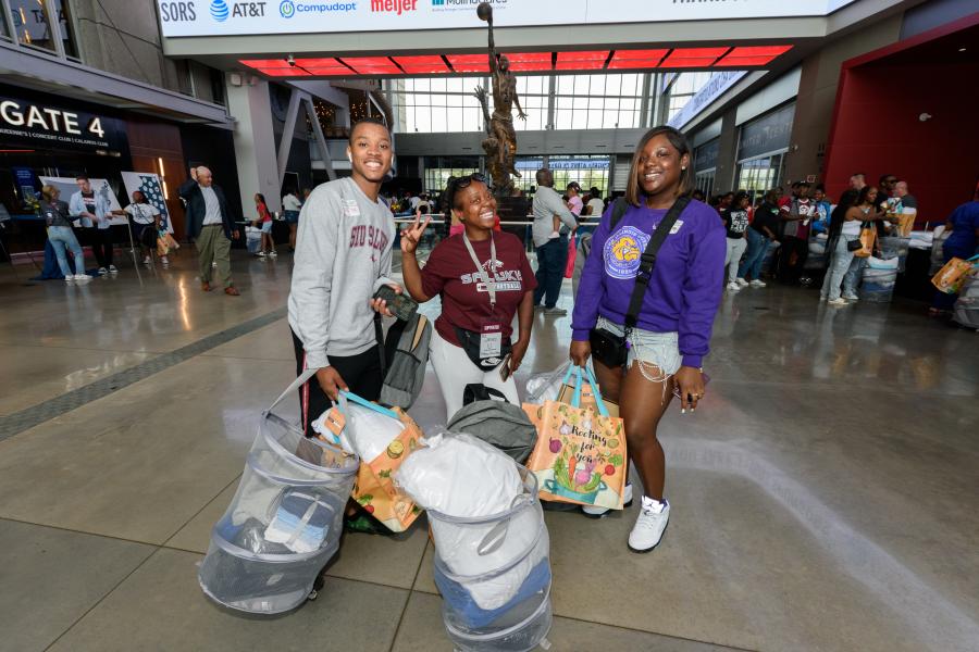 Teens carrying college supplies posing for a picture.