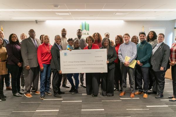 A group of people standing in a room holding a giant check.